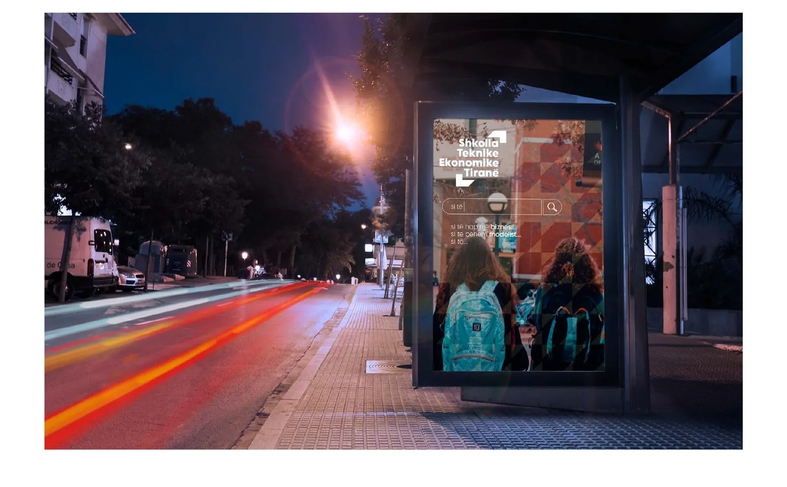 A bus-stop advertisement for the school at night