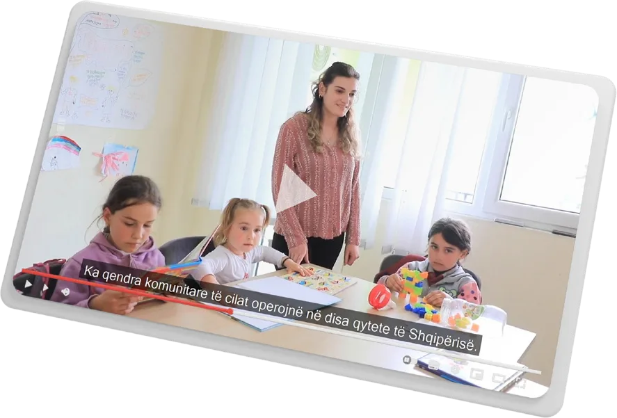 A frame from the documentary: children drawing at a table in a community centre with an educator